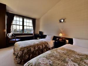 茅野Petit Hotel Kanan的酒店客房设有两张床和窗户。