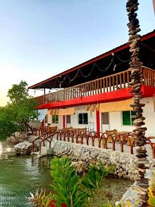 阿拉米诺斯CASA BOLO IN ALAMINOS with HIDDEN WHITE BEACH near 100 Islands的水边的一座配有桌椅的建筑