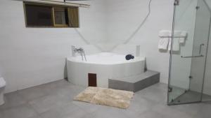 阿克拉The Winford Boutique Hotel Airport的白色的浴室设有浴缸和玻璃淋浴间。