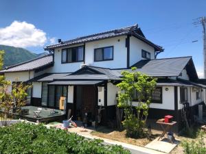 安昙野市Azumino Fukuro Guesthouse - Vacation STAY 27117v的黑色屋顶的白色房子