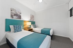 麦夸里港Club Wyndham Flynns Beach, Trademark Collection by Wyndham的蓝色和白色的酒店客房内的两张床