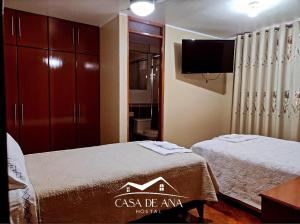 纳斯卡Hostal Casa de Ana的配有电视和卧室的客房内的两张床