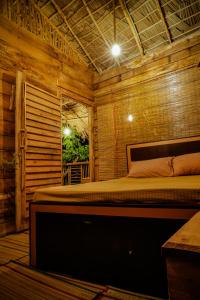 Eco Bliss Cottages - Thanamalwila的木制客房内的一间卧室,配有一张床