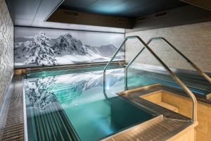 达沃斯Precise Tale Seehof Davos的一座墙上挂有山壁画的室内游泳池