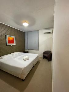 纽卡斯尔梅菲尔德汽车旅馆的卧室配有一张白色大床和一把椅子