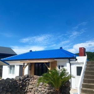 济州市Gawkji House 곽지집的蓝色屋顶和石墙的房子