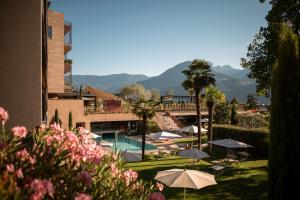 梅拉诺穆彻勒酒店的一个带游泳池、遮阳伞和山脉的度假胜地