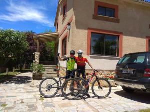 Palazuelos de EresmaCasa Rural Las Tuyas en Segovia的两个人站在自行车旁的房子前