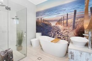 凯阿玛Driftwood Beach House的带浴缸的浴室和海滩画
