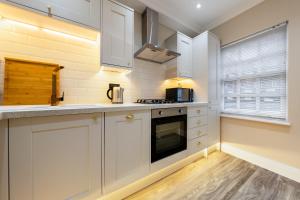 伦敦Brand New London Luxury House - Sleeps 8的厨房配有白色橱柜和炉灶。