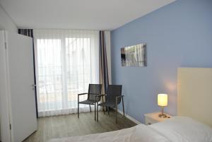 埃肯弗德Apartmenthaus Hafenspitze Ap 42 "Segler", mit Sauna, Blickrichtung offene See - a72332的酒店客房带床、椅子和窗户