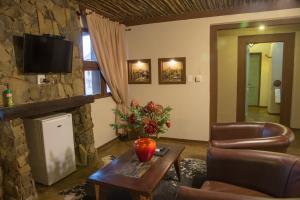 布隆方丹Emoya Basotho Lodge的客厅配有桌子和石墙