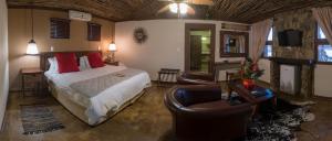 布隆方丹Emoya Basotho Lodge的一间卧室配有一张床,客厅配有沙发
