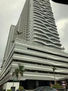 马尼拉Cosy Luxy Coast Residences Staycation的一座高大的建筑,前面有棕榈树