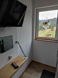 加沃尔金卡Gościniec Śliwkula的客房设有电视和带窗户的书桌。