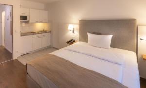 慕尼黑Downtown Vi Vadi Hotel的一间带白色大床的卧室和一间厨房