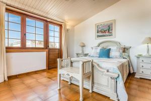 萨尔加LA CALMA Espectacular villa con jardín y piscina en Menorca的一间卧室配有一张床、一把椅子和窗户。