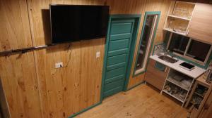 富伊港Tiny Fuy的一间设有绿门的房间,墙上有一台电视机