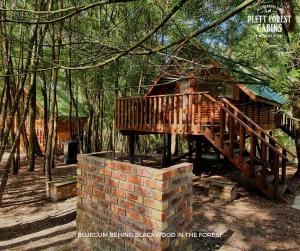 普利登堡湾Plett Forest Cabins的小屋旁砖墙上的木桥