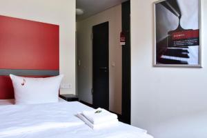 耶拿Hotel VielHarmonie的卧室配有白色的床和墙上的海报