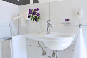 耶拿Hotel VielHarmonie的浴室配有水槽和紫色花瓶