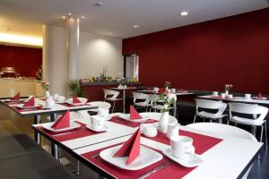 耶拿Hotel VielHarmonie的餐厅配有桌椅和红色餐巾