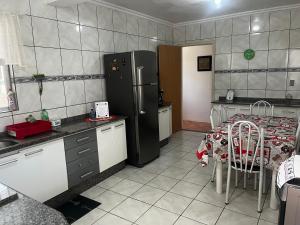 纳韦甘蒂斯Casa de praia da Kenna, centro的厨房配有桌子和黑冰箱。