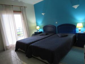 西尔维拉Hotel Apartamento Praia Azul的一间蓝色卧室,配有两张床和窗户