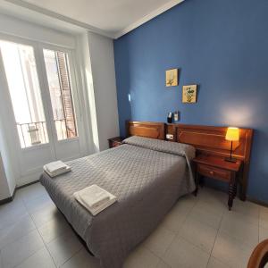 马德里泛美旅馆的一间卧室设有一张床和蓝色的墙壁