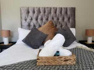 阿尔伯顿Bosveld In Die Stad Guesthouse的一张带毛巾篮和枕头的床