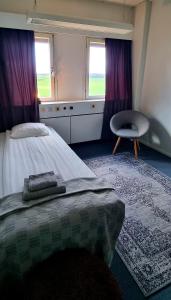 埃斯基尔斯蒂纳Hotell Tre Systrar的一间卧室配有一张床和一把椅子,还有两个窗户