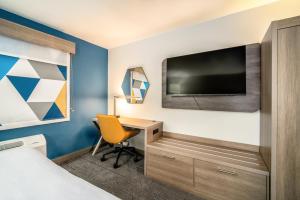 梅萨Holiday Inn Express & Suites Phoenix - Mesa West, an IHG Hotel的酒店的客房,配有书桌和墙上的电视