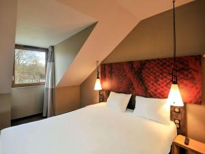 迈松拉菲特宜必思曼森拉斐特酒店的卧室配有一张带两个枕头的大白色床