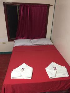 玉米岛Jackson Guest House的一张红色的床,上面有两条白色的毛巾