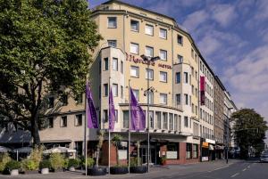 杜塞尔多夫杜塞尔多夫市中心美居酒店的前面有紫色旗帜的建筑