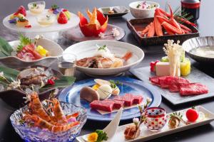 丰冈市汤乐城崎温泉花园旅馆的一张桌子上放着许多盘子的食物