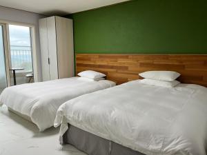 济州市Hill Hotel的卧室设有两张床铺和绿色的墙壁