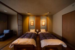 南小国町Yukyo no Hibiki Yusai的一间带两张床和椅子的房间