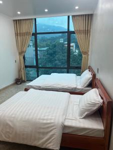 河江Minh Vân Hostel的带大窗户的客房内的两张床