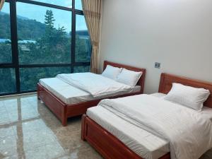河江Minh Vân Hostel的带大窗户的客房内的两张床