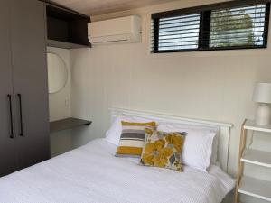 陶朗加Pukeko Lane的卧室配有带枕头的白色床和窗户。