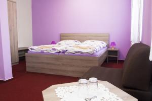 伊赫拉瓦Motel Pávov的一间卧室配有一张紫色墙壁的床和两张桌子