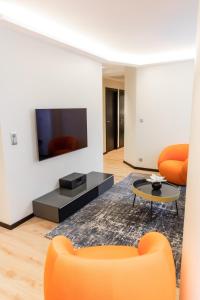 第戎Suite Romanée 6 personnes vue Cathédrale 2 Places de parking的客厅配有橙色家具和平面电视。
