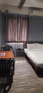 索拉普Hotel Ashirwad, Solapur的一间卧室配有一张床、一张桌子和窗帘