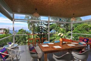 芭东海滩Daydream villa resort的一间带桌椅和大窗户的用餐室