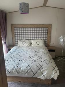 布莱克浦Luxury 6 Berth Caravan, Marton Mere的一间卧室配有一张大床和木制床头板