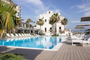 波蒂奇Hotel & Resort Tre Fontane Luxury的白色建筑前的游泳池