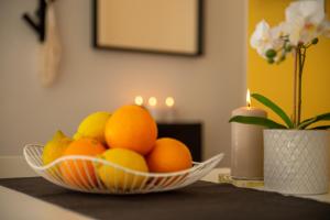 里米尼Corso51 Suite Apartments的桌上放着一碗橘子和柠檬,放着蜡烛