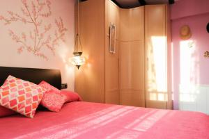 莱索Apartamento Jaizkibel by SanSe Holidays的一间卧室配有粉红色的床和红色枕头