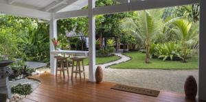 维拉港Papaya Villa的一个带桌椅的门廊和一个花园